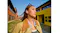 Front view of a woman with an earbud looking upward near colourful architecture Front view of a woman with an earbud looking upward near colourful architecture
