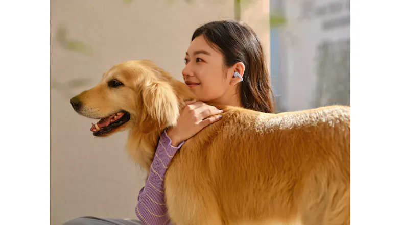 A woman wearing a purple earbud is hugging a golden retriever dog A woman wearing a purple earbud is hugging a golden retriever dog