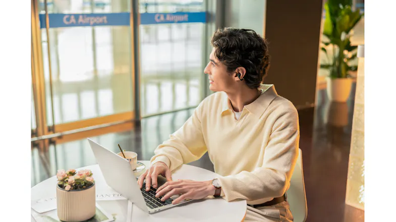 Indoor view of a man working on a laptop with earbuds Indoor view of a man working on a laptop with earbuds