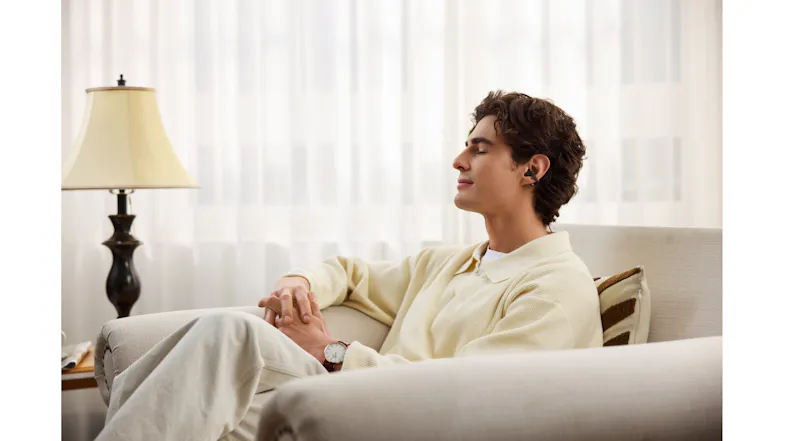 Indoor lifestyle view of a man with an earbud relaxing on a sofa Indoor lifestyle view of a man with an earbud relaxing on a sofa