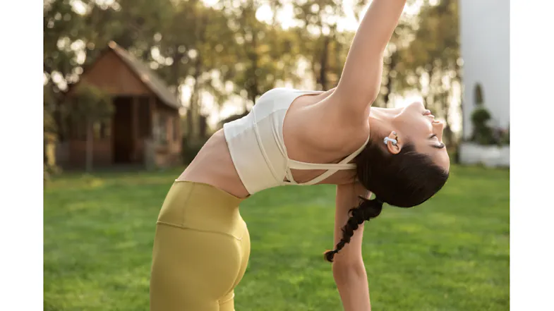 Dynamic view of a person wearing an earbud while stretching outdoors Dynamic view of a person wearing an earbud while stretching outdoors