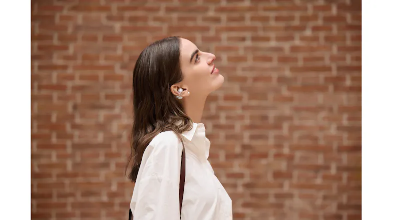 Side view of a person looking upward against a brick wall with earbuds Side view of a person looking upward against a brick wall with earbuds