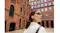 Low-angle view of a person with white earbuds looking up near brick architecture Low-angle view of a person with white earbuds looking up near brick architecture