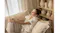 Indoor lifestyle view of a woman relaxing on a cosy sofa while wearing earbuds Indoor lifestyle view of a woman relaxing on a cosy sofa while wearing earbuds