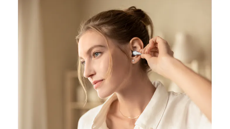 Close-up view of a woman adjusting her earbud indoors Close-up view of a woman adjusting her earbud indoors