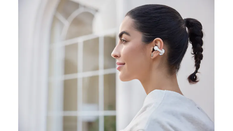 Side view of a person with tied hair looking forward with earbuds Side view of a person with tied hair looking forward with earbuds