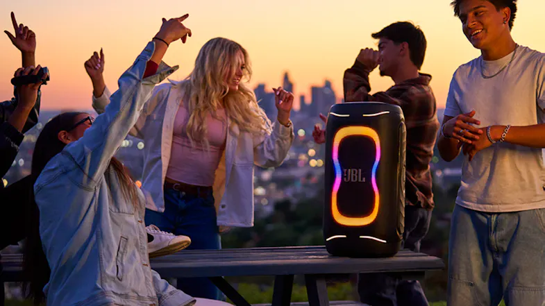 The speaker is propped on a table while a crowd parties around it The speaker is propped on a table while a crowd parties around it
