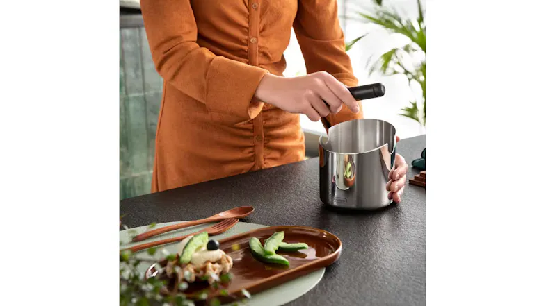 Person removing the knock bar from a stainless steel coffee knock box for cleaning on a kitchen counter Person removing the knock bar from a stainless steel coffee knock box for cleaning on a kitchen counter