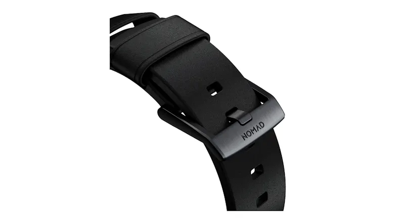 Close-up view of a black Nomad watch strap buckle with engraved branding and custom dark metal hardware Close-up view of a black Nomad watch strap buckle with engraved branding and custom dark metal hardware