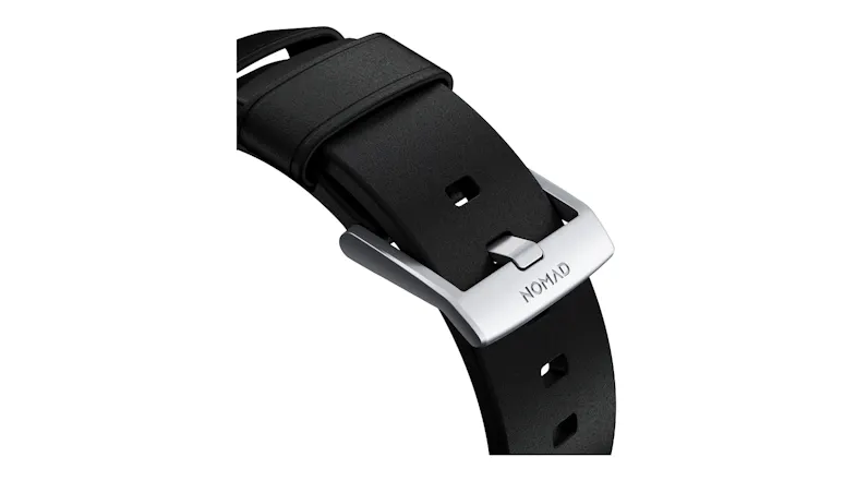 Close-up view of a black Nomad watch strap buckle with engraved branding and custom dark metal hardware Close-up view of a black Nomad watch strap buckle with engraved branding and custom dark metal hardware