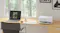 Home office desk with a laptop and Epson EcoTank printer producing a colour document beside a large window Home office desk with a laptop and Epson EcoTank printer producing a colour document beside a large window