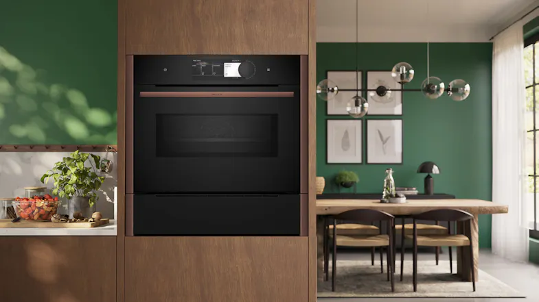 Built-in black Neff oven and steam drawer with bronze accents, integrated into modern wood cabinetry Built-in black Neff oven and steam drawer with bronze accents, integrated into modern wood cabinetry