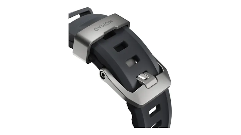 A close-up view of a rubber watch strap featuring a titanium buckle mechanism and strap loop with Nomad engraving A close-up view of a rubber watch strap featuring a titanium buckle mechanism and strap loop with Nomad engraving
