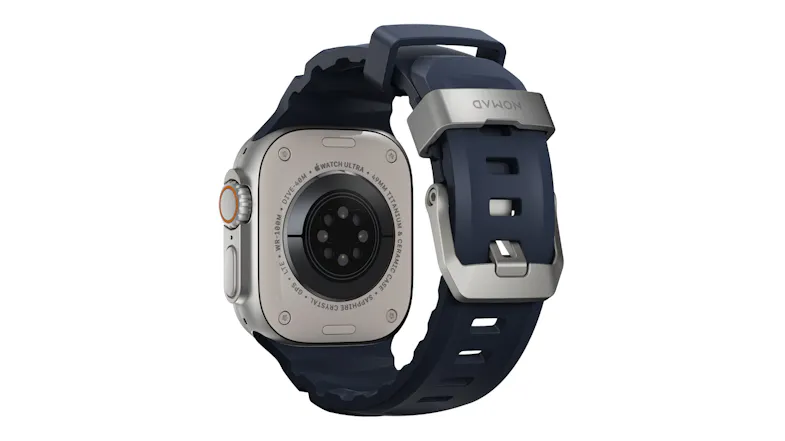 Rear view of Apple Watch Ultra showing back sensor array, rubber band, and titanium buckle engraved with Nomad Rear view of Apple Watch Ultra showing back sensor array, rubber band, and titanium buckle engraved with Nomad