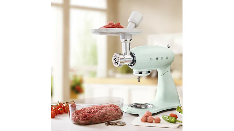 Food grinder mounted on a pastel green Smeg stand mixer. Displayed in a kitchen environment Food grinder mounted on a pastel green Smeg stand mixer. Displayed in a kitchen environment