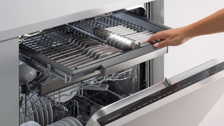 Close-up of the upper rack inside the Fisher & Paykel dishwasher. A hand adjusts the rack Close-up of the upper rack inside the Fisher & Paykel dishwasher. A hand adjusts the rack