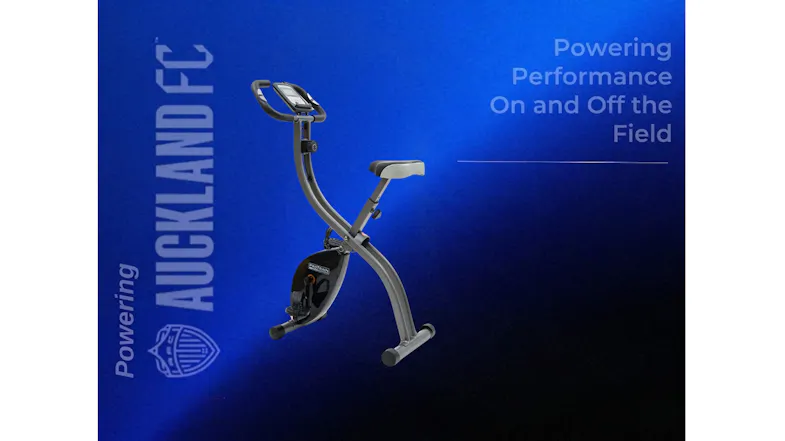 Grey folding exercise bike shown on a blue graphic with "Powering Auckland FC" branding and logo Grey folding exercise bike shown on a blue graphic with "Powering Auckland FC" branding and logo