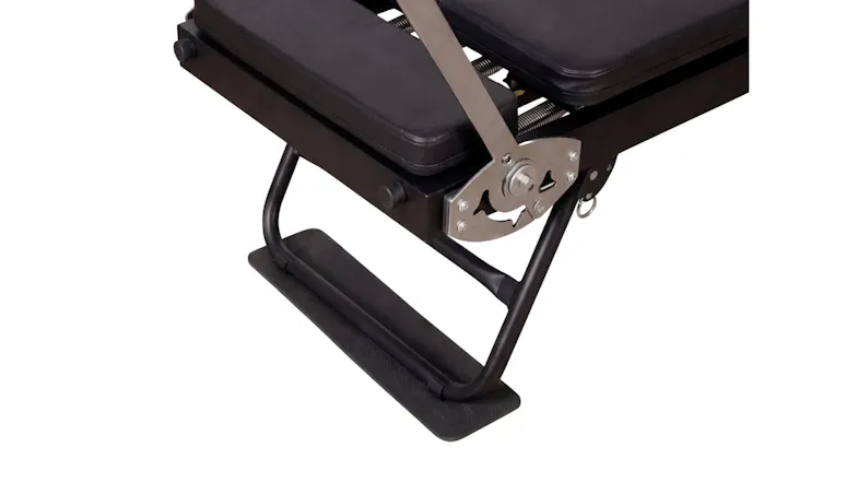 Top-down view focusing on the padded black headrest and frame end of a Pilates reformer machine Top-down view focusing on the padded black headrest and frame end of a Pilates reformer machine