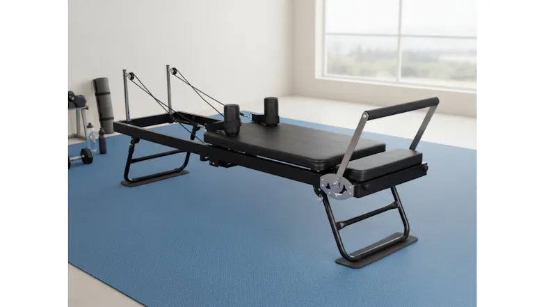 A black Pilates reformer positioned on a blue rug inside a bright room with weights visible A black Pilates reformer positioned on a blue rug inside a bright room with weights visible
