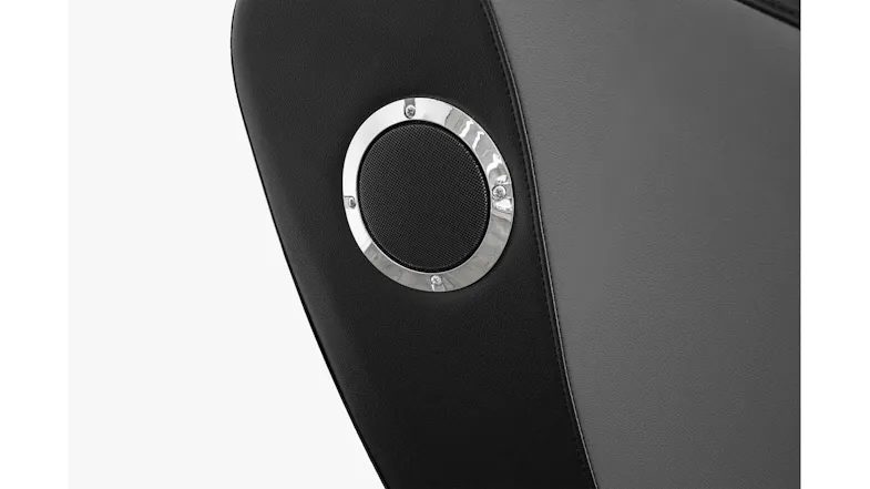 Close-up of integrated round side speaker with chrome trim ring built into outer casing of Novello massage chair unit Close-up of integrated round side speaker with chrome trim ring built into outer casing of Novello massage chair unit