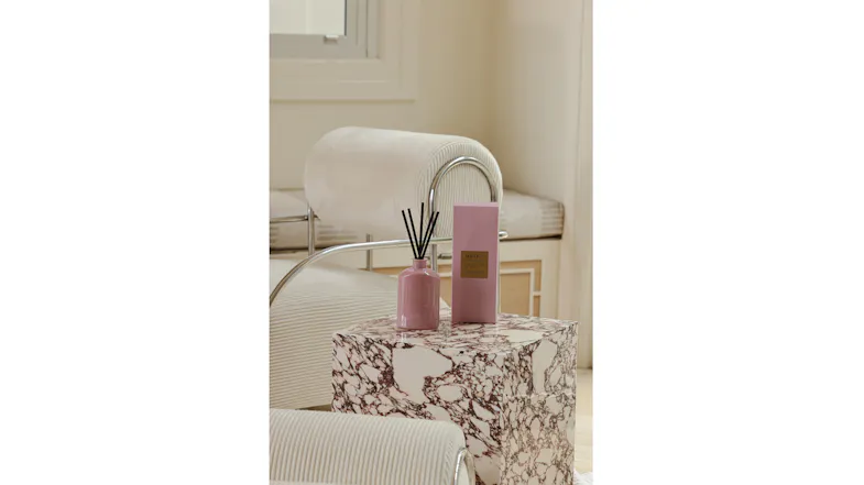 Interior setting featuring a pink diffuser and box on a marble side table Interior setting featuring a pink diffuser and box on a marble side table