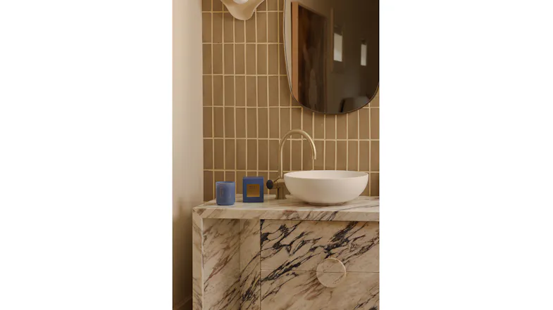 Modern vanity displaying a candle and packaging beside vessel sink Modern vanity displaying a candle and packaging beside vessel sink