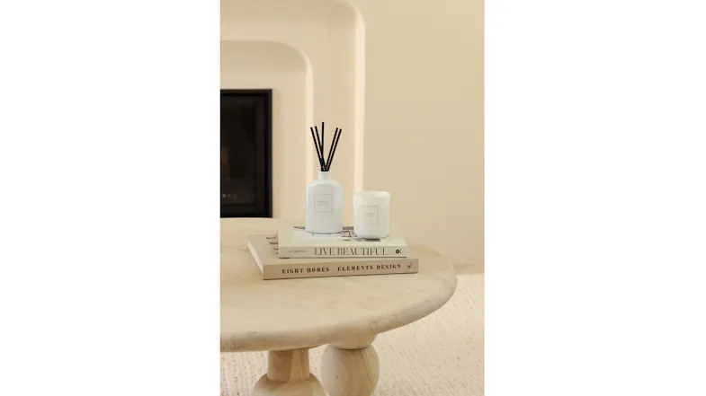 Cosy setting featuring white reed diffuser and candle on coffee table Cosy setting featuring white reed diffuser and candle on coffee table