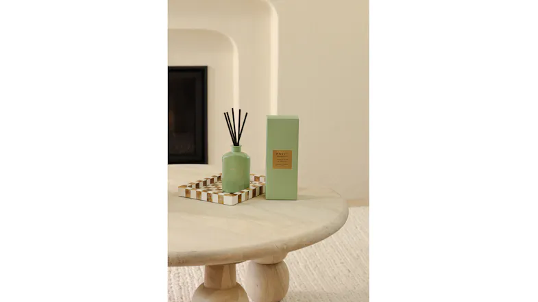 Living space highlighting a green diffuser and packaging on a checkered tray Living space highlighting a green diffuser and packaging on a checkered tray