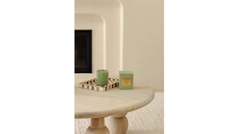 Living space highlighting a lit candle and packaging on checkered tray Living space highlighting a lit candle and packaging on checkered tray