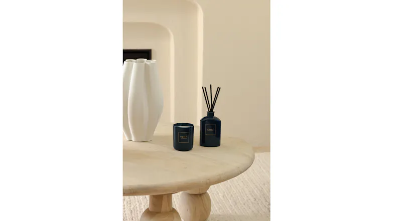 Warm setting highlighting a reed diffuser and candle on coffee table Warm setting highlighting a reed diffuser and candle on coffee table