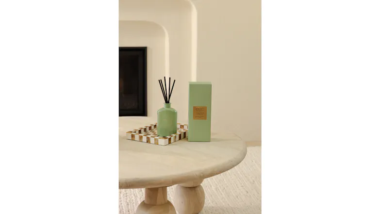 Moss St. 100ml mini reed diffuser bottle and green box styled on a checkered tray over a wooden table Moss St. 100ml mini reed diffuser bottle and green box styled on a checkered tray over a wooden table