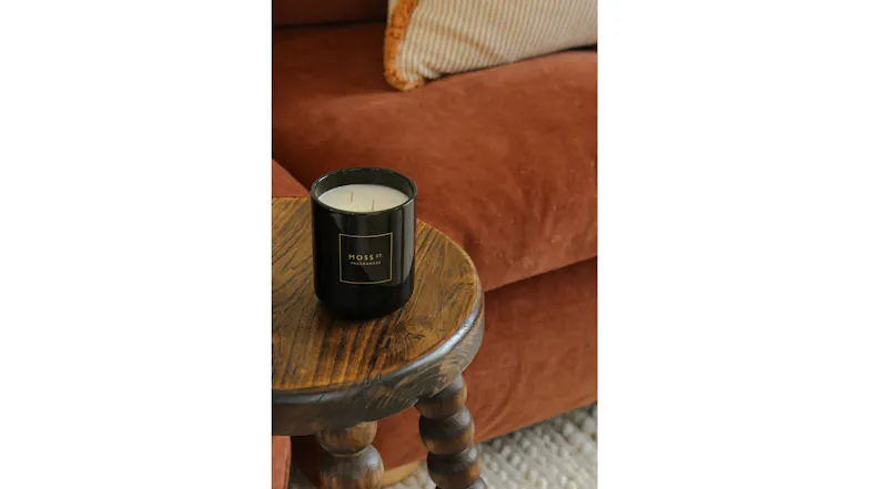 Warm living area showcasing a lit candle on rustic wooden table Warm living area showcasing a lit candle on rustic wooden table
