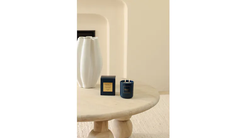 Minimalist room featuring a lit blue candle and box near a white vase Minimalist room featuring a lit blue candle and box near a white vase