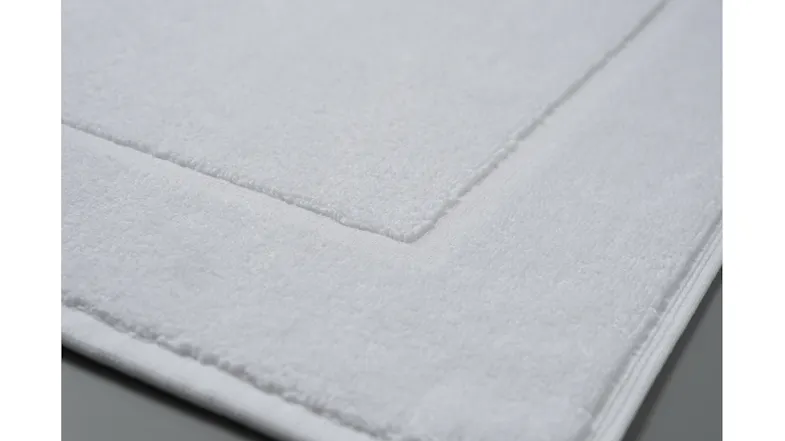 Close-up of the white plush bath mat, highlighting its soft texture and stitched border detail Close-up of the white plush bath mat, highlighting its soft texture and stitched border detail