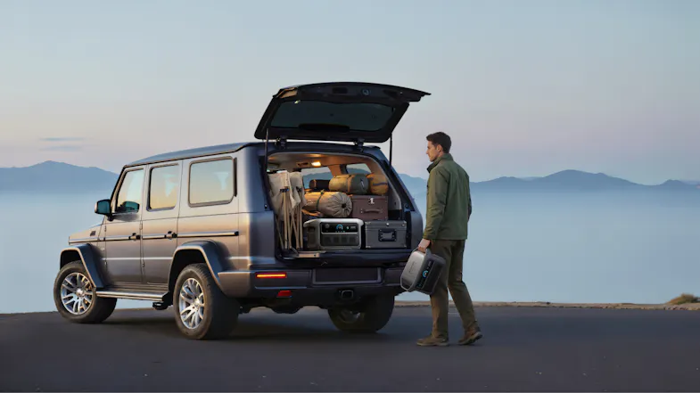 Person loading an Anker SOLIX portable power station into an SUV packed for travel or camping Person loading an Anker SOLIX portable power station into an SUV packed for travel or camping
