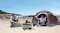 Beach campsite featuring a portable power station, foldable solar panels, and a cooling fan Beach campsite featuring a portable power station, foldable solar panels, and a cooling fan