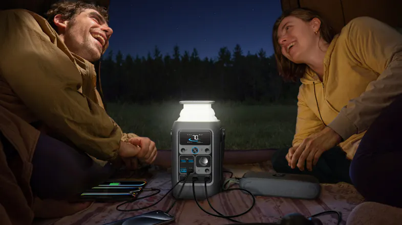 Campers using a portable power station with a built-in lantern for off-grid power after dark Campers using a portable power station with a built-in lantern for off-grid power after dark