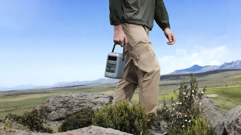 A person carrying a portable power station during outdoor hiking in a mountain landscape A person carrying a portable power station during outdoor hiking in a mountain landscape