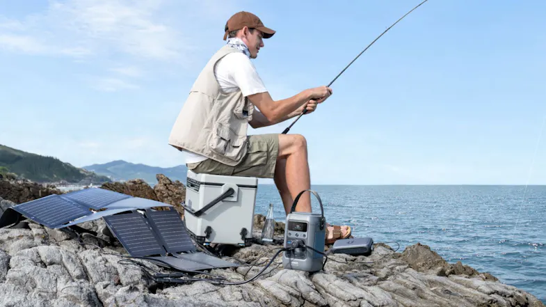 Solar-powered portable generator charging outdoor gear during a fishing trip on coastal rocks Solar-powered portable generator charging outdoor gear during a fishing trip on coastal rocks