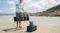 A foldable solar panel connected to a portable power station on a beach camping setup A foldable solar panel connected to a portable power station on a beach camping setup