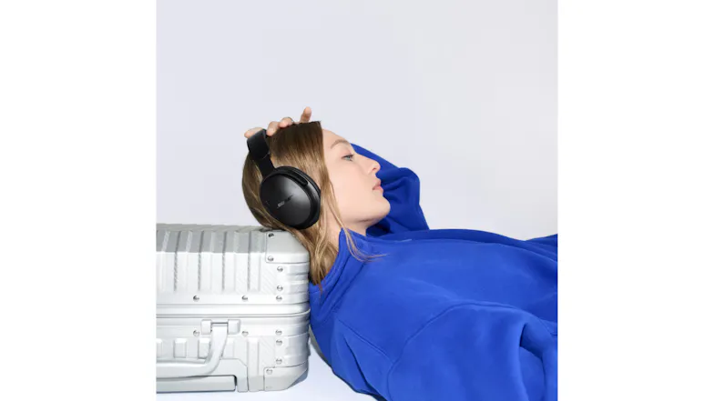 Woman lying on luggage featuring black headphones over her ears Woman lying on luggage featuring black headphones over her ears