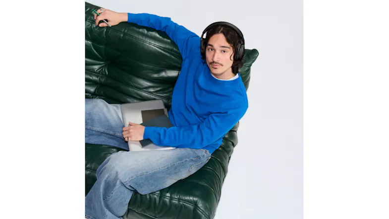 Man on sofa with laptop showcasing Bose headphones on head Man on sofa with laptop showcasing Bose headphones on head