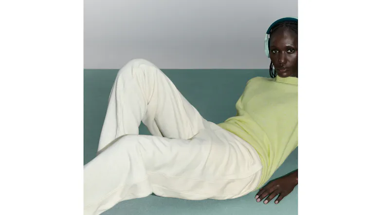 Woman lying down featuring light green headphones over her ears Woman lying down featuring light green headphones over her ears