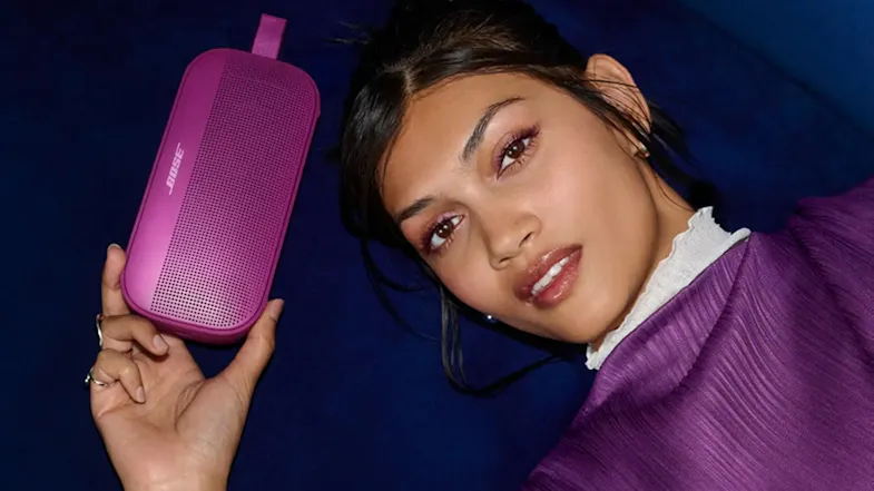 Woman holding the Bose speaker showcasing its compact size Woman holding the Bose speaker showcasing its compact size