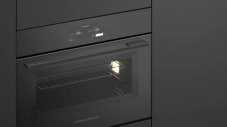 An angled side view of the oven integrated into a sleek black wall An angled side view of the oven integrated into a sleek black wall