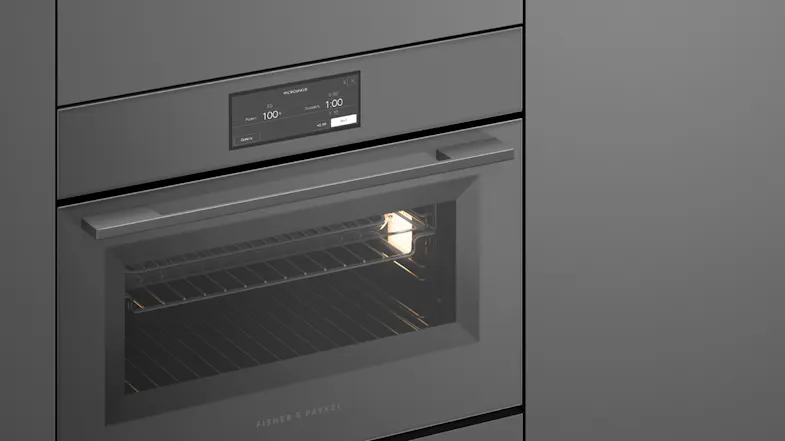 An angled side view of the oven integrated into a sleek grey wall An angled side view of the oven integrated into a sleek grey wall