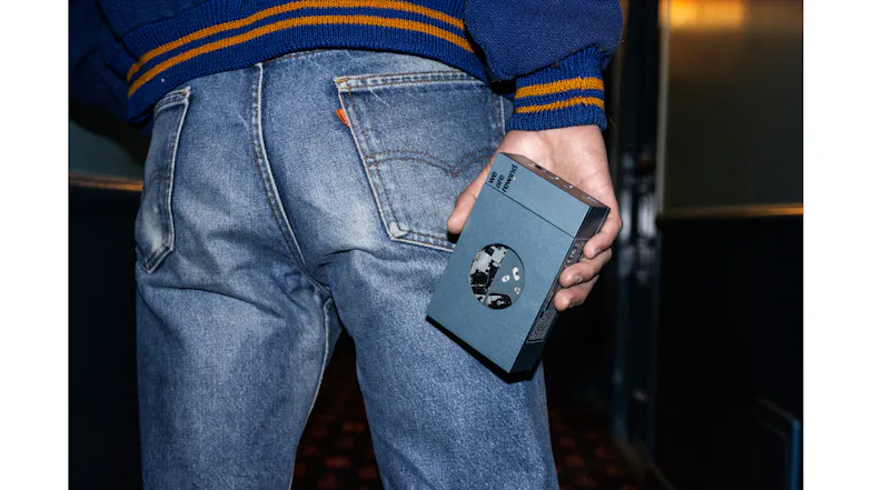 Close-up lifestyle shot of the blue cassette player held in hand, highlighting the circular cassette window Close-up lifestyle shot of the blue cassette player held in hand, highlighting the circular cassette window