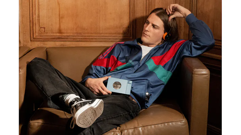 Person reclining on a leather chair while holding the We Are Rewind Kurt portable cassette player in blue Person reclining on a leather chair while holding the We Are Rewind Kurt portable cassette player in blue
