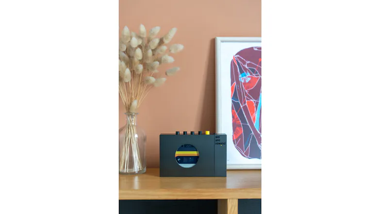 Wide lifestyle shot of the grey Bluetooth cassette player displayed on a shelf with decorative accessories Wide lifestyle shot of the grey Bluetooth cassette player displayed on a shelf with decorative accessories