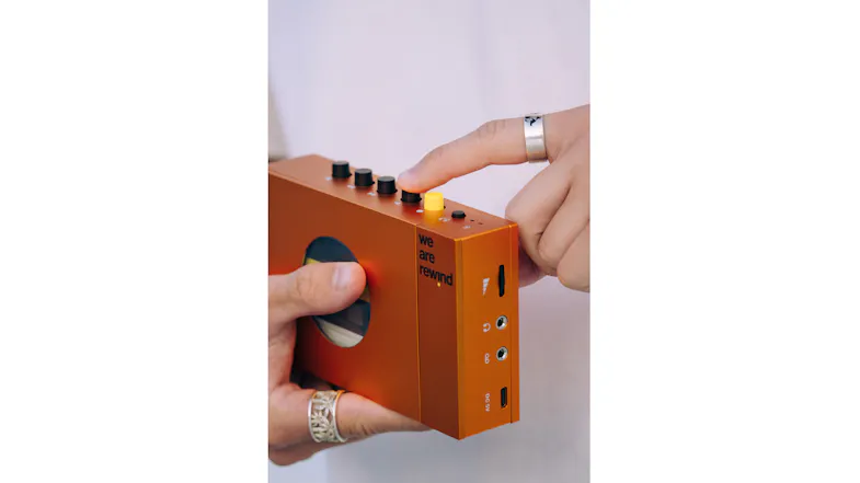 Close-up of hands operating the orange cassette player, demonstrating the device’s portable size Close-up of hands operating the orange cassette player, demonstrating the device’s portable size
